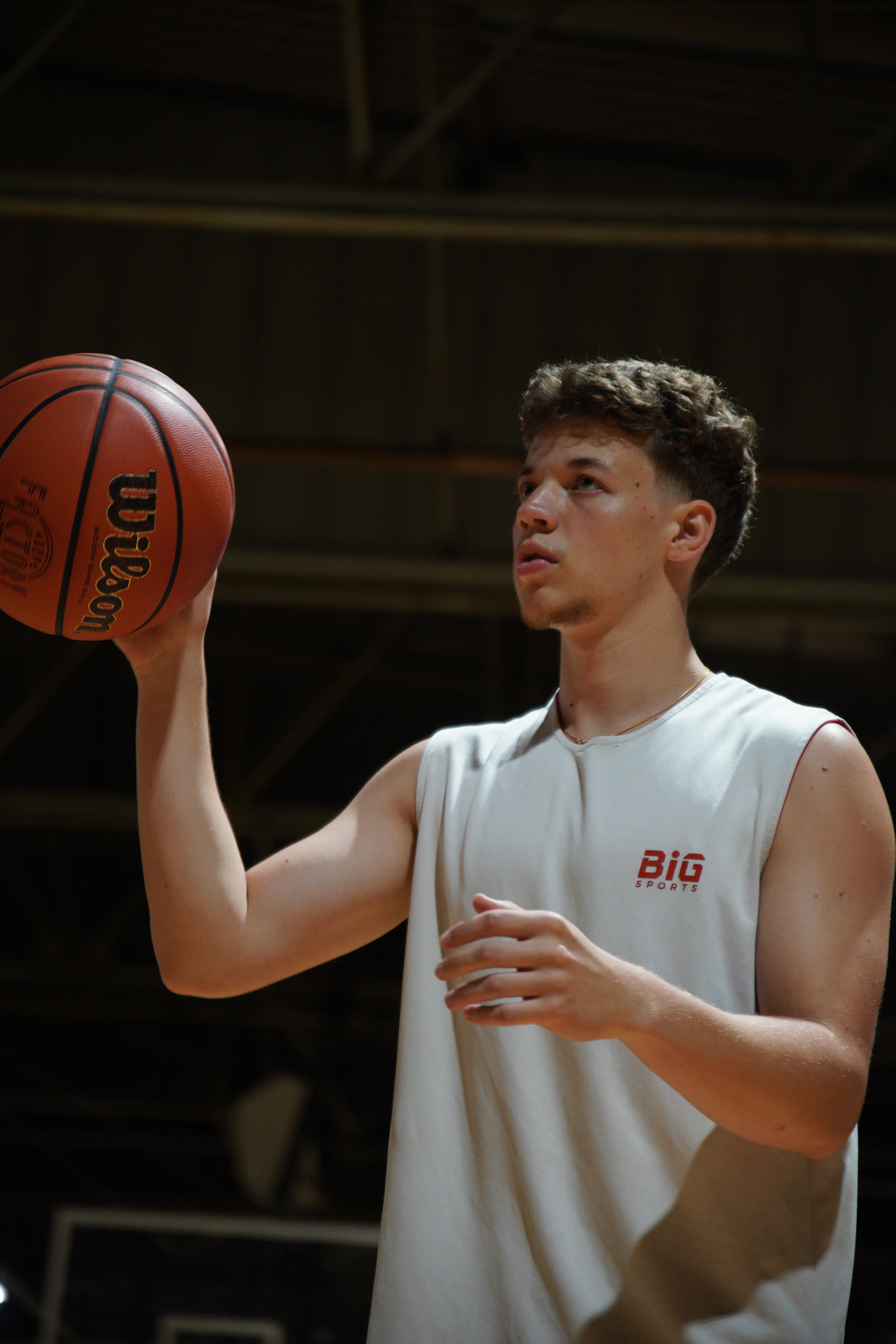 Trois joueurs, ballon en main, dans un gymnase